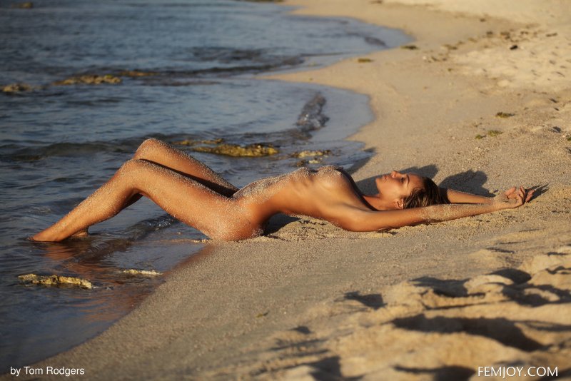 Загорелая худая модель в песке на пляже - фото