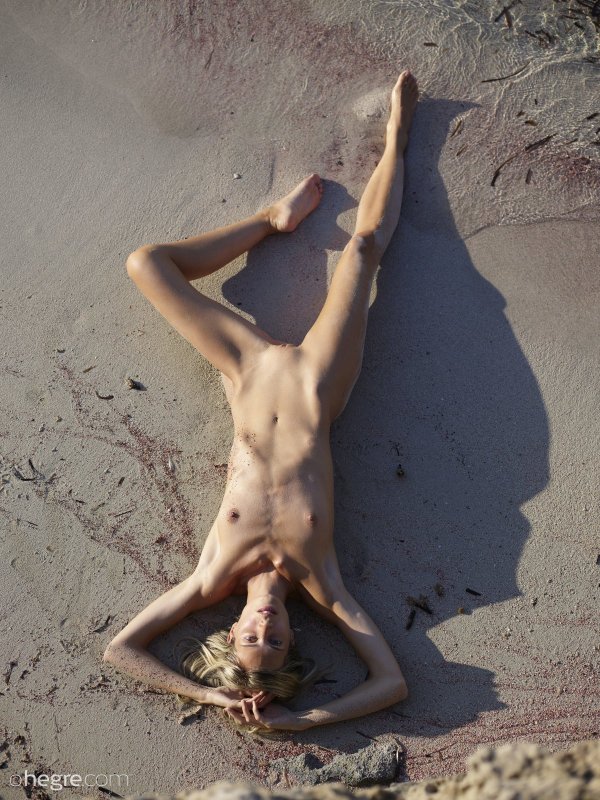 Голожопая тощая девка в песке на пляже - фото