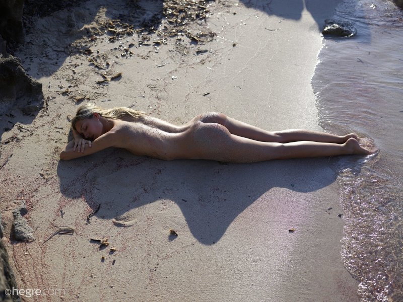 Голожопая тощая девка в песке на пляже - фото